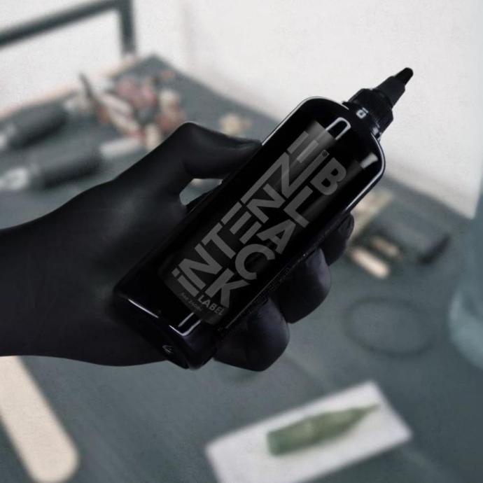 Tattoo Artist holding a bottle of Intenze Black Label Tattoo Ink